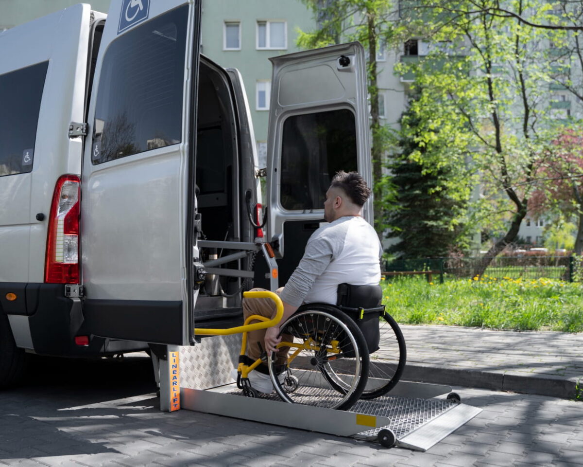 Ein älterer Mann steht lächelnd an der geöffneten Tür eines Autos.