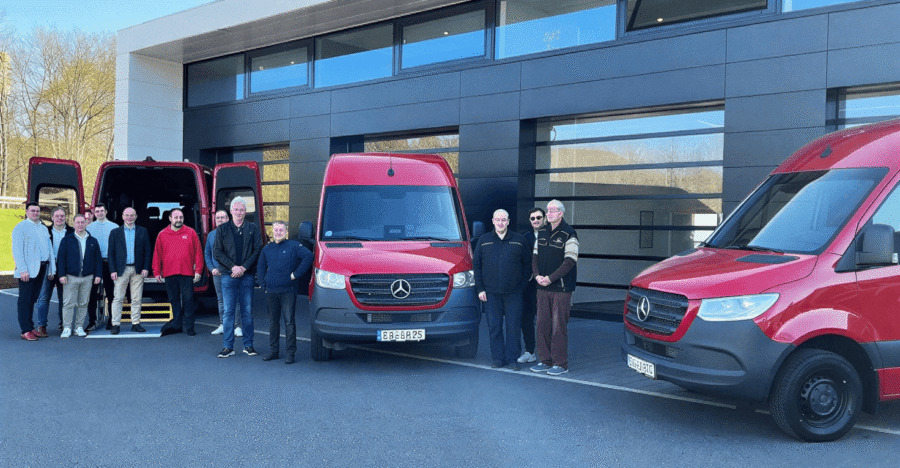 Das CareMobil-Team steht vor drei roten Kleinbussen am Standort Eisenach.